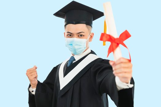 young male graduation wearing face mask and holding his college certificate during the coronavirus pandemic