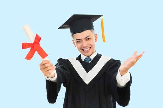 Excited young man in  black graduation gown and cap holding a diploma