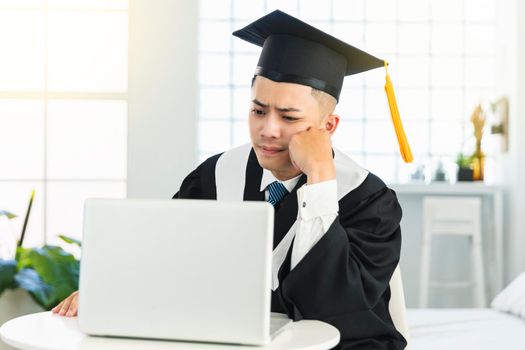 frustrated male graduation trying to learn online at home