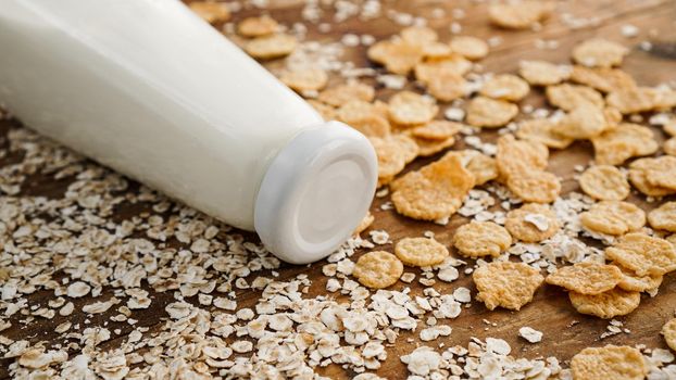 Fresh milk bottle on wooden background with oats and cereals