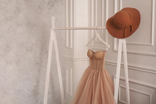 Beige dress and hat on a hanger. White Scandinavian style