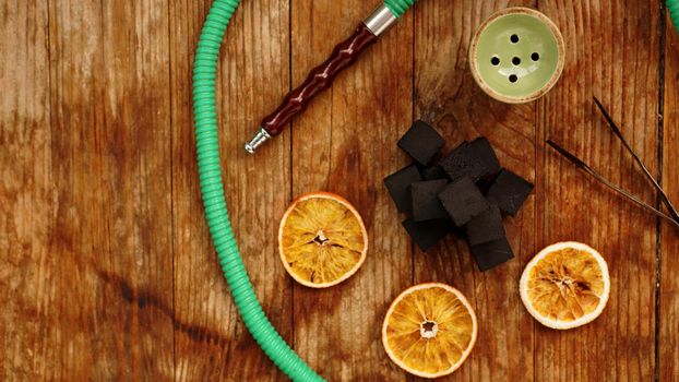 Coals for hookah on wooden background with dry oranges