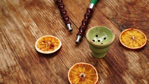 Hookah bowl on wooden background with dry oranges