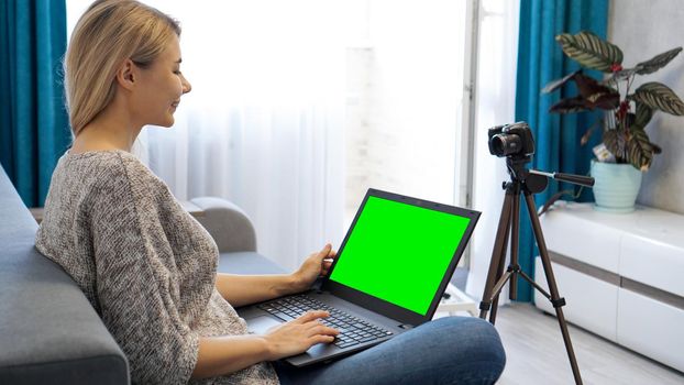 View of camera on tripod and laptop with green screen chromakey