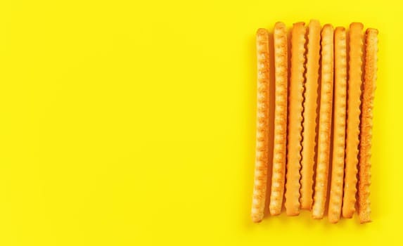 Grissini, also known as breadsticks on yellow board, view from above space for text left side