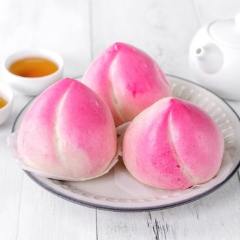 Pink Chinese peach birthday bun food on white table background.