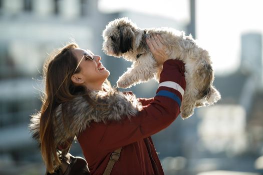 Portrait of a smiling woman having fun with her cute Shih Tzu dog outdoor.