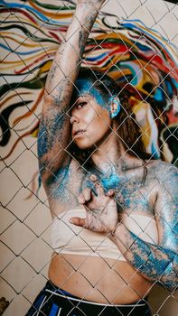 Brunette girl behind the net. Portrait of woman with blue sparkles on her face