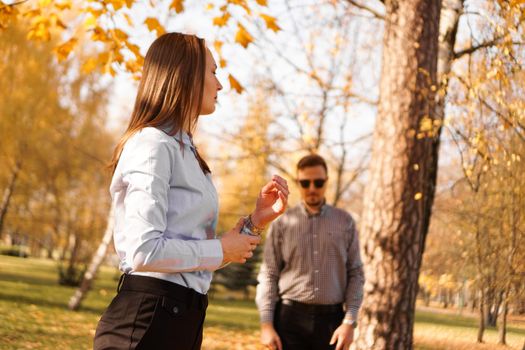 Unknown man in sunglasses watches a woman in park