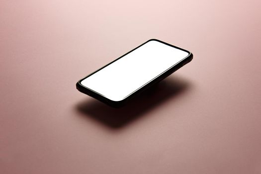 Minimalistic mock up flat image design of a mobile phone with copy space and white scree to write over it over a flat pastel pink background