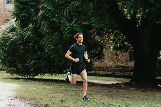 A young male doing a sprint in the park during a training day while doing fitness