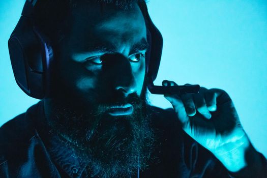 A young man with beard holding a gaming headset on serious face