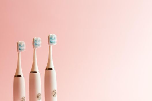 Conceptual shot of electrical toothbrush over a pink pastel background with copy space