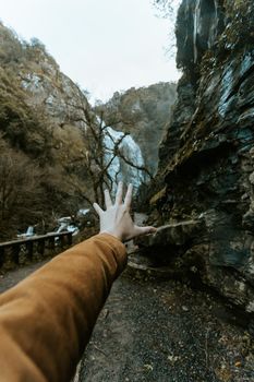 A hand in front of a massive waterfall on moody tones with liberty concept and travel on vintage tones with copy space