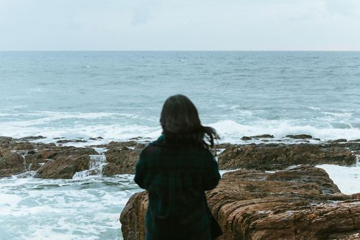 Woman giving the back to the camera in front of a massive ocean with copy space