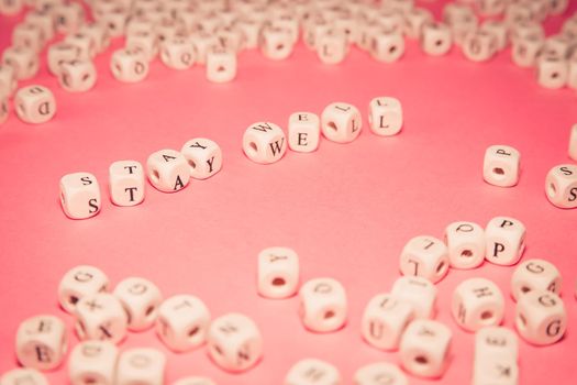 White dices over a pink pastel background with stay well message, wellness and life concepts