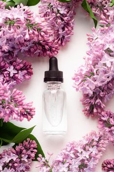 Hyaluronic acid bottle and lilac on a white background . Beauty container. Skin care. Vitamins for the skin. Rejuvenation. Female beauty. An article about the benefits of hyaluronic acid. Article about the choice of hyaluronate. Copy space. A branch of lilac. Flowering .