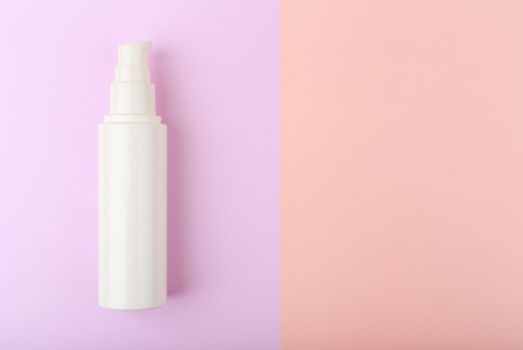 Face cream in white unbranded tube against purple and pink background with copy space