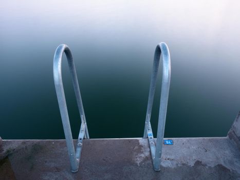 Swimming ladder from stainless steel for descent into sea water on pier. Silent bay