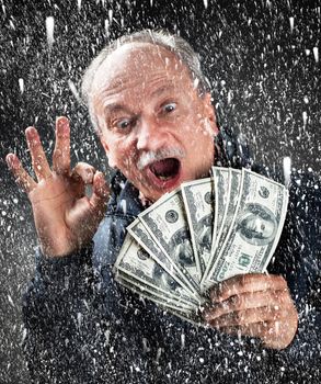 man with a bundle of dollars in snowfall
