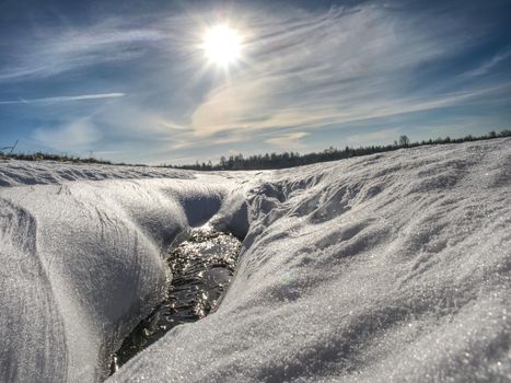 Hole in icy snow with sun flares. Lovely winter 