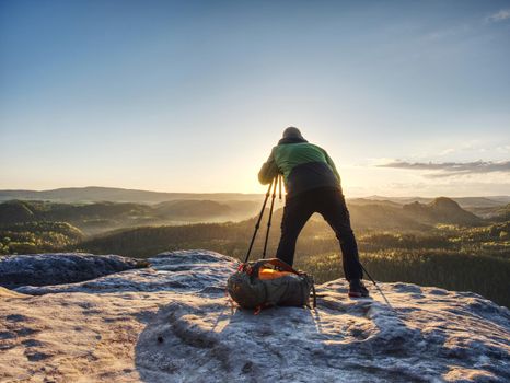 Artist set camera and tripod to photograph sunrise on summit
