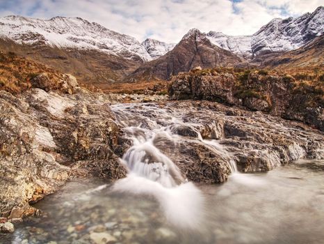 Waterfall and rapids against to snowy mountains