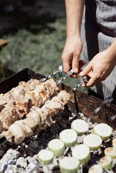 Close up of kebabs on skewers, man grilling meat outdoors