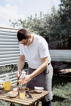 Young man grilling kebabs on skewers, man grilling meat outdoors