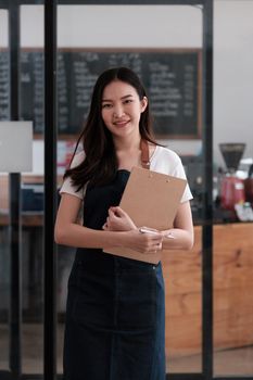 At her coffee shop, the business owner or barista with menu and waiting order from first customer back to open the shop after COVID-19.