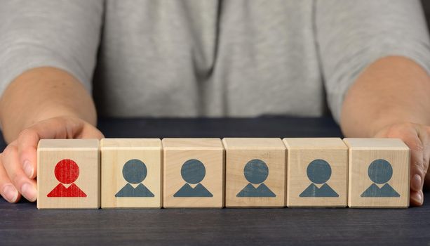 female hands hold wooden cubes with figurines. Employee search concept, staff recruitment
