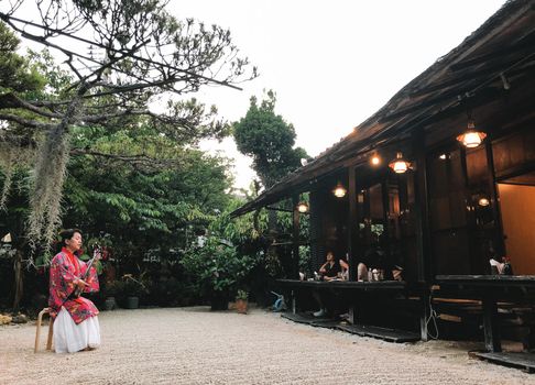 Naha Okinawa, May 21, 2019 - A woman playing a sanshin wearing a traditional Okinawan costume in the restaurant.