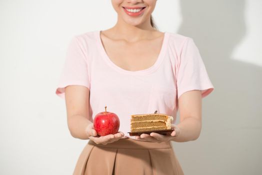 The girl in one hand has an apple, in the other hand a cake.
