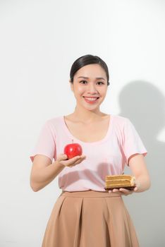 The girl in one hand has an apple, in the other hand a cake.