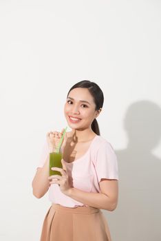Go green. Young beautiful woman enjoying a healthy raw fruit vegetable juice. Studio shot.