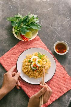 Hand uses chopsticks to pickup tasty noodles 
