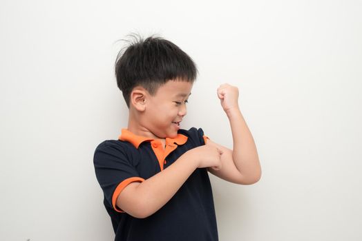 Young asian boy pointing his bicep to tell he is strong