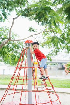 Little boy in cap climb on jungle gym at park