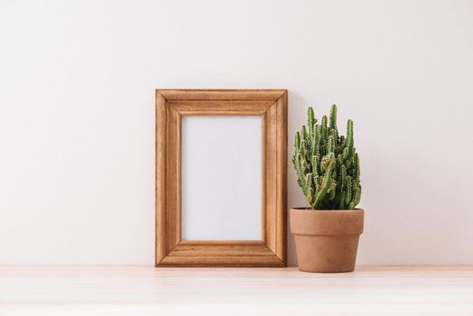 mock up frame with cactus pot on wooden floor
