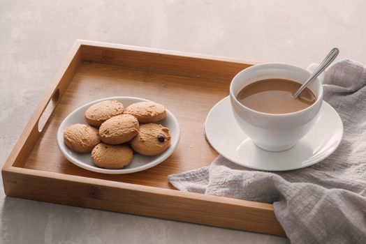 Cup of coffee with milk or cappuccino with cookies on light stone background. Drink with caffeine or cocoa with milk. Coffee break concept. 