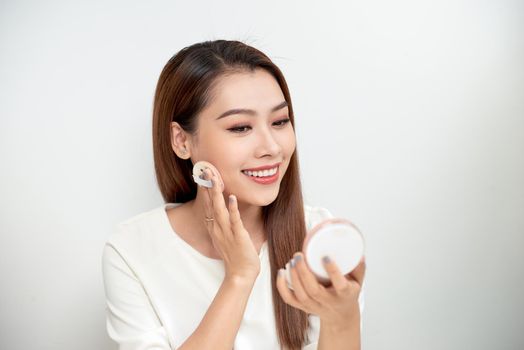 Face Make-Up. Closeup Of Sexy Female Applying Dry Powder Foundation Looking In Mirror. Portrait Of Young Woman Putting Makeup Powder With Cosmetic Cushion On Her Facial Skin Indoors. High Resolution