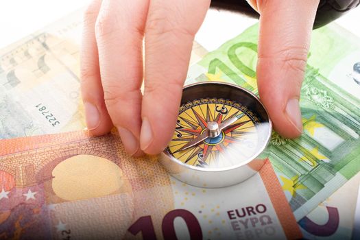 Hand holding compass  on Euro banknotes as business,  finance concept