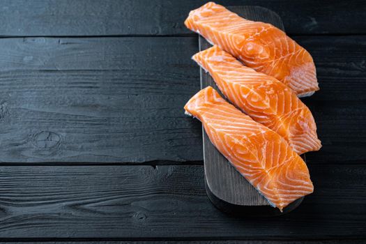 Portion of salmon fillet, on black wooden table with space for text