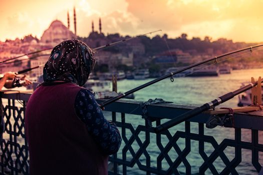 Old woman fishing on Galata bridge. Vacation in Istanbul. 
