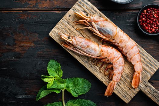 King prawns with herbs over dark rustic wooden background, flat lay with copy space