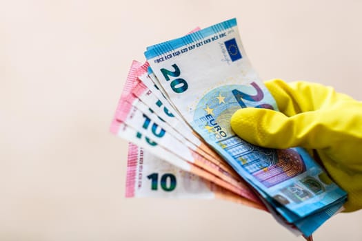 World money concept, hand with gloves receiving, giving or holding EURO banknote, isolated on blurred background. Corona virus COVID-19 outbreak. Concept of prevention virus spread