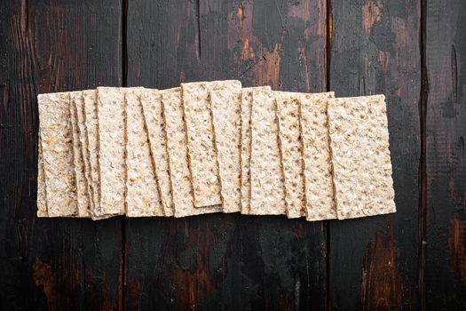 Whole grain crisp bread, on old dark wooden table background, top view flat lay, with copy space for text