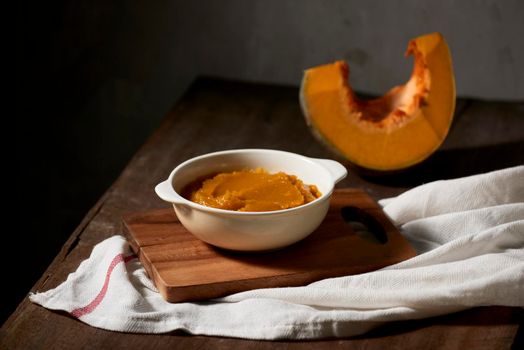 Pumpkin puree in a bowl on wooden background