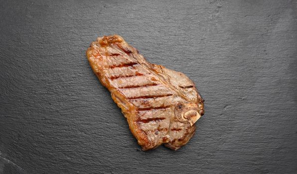 whole fried New York beef steak on a black board, striploin doneness rare
