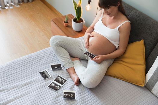 Pregnant woman looking to the ultrasound pictures